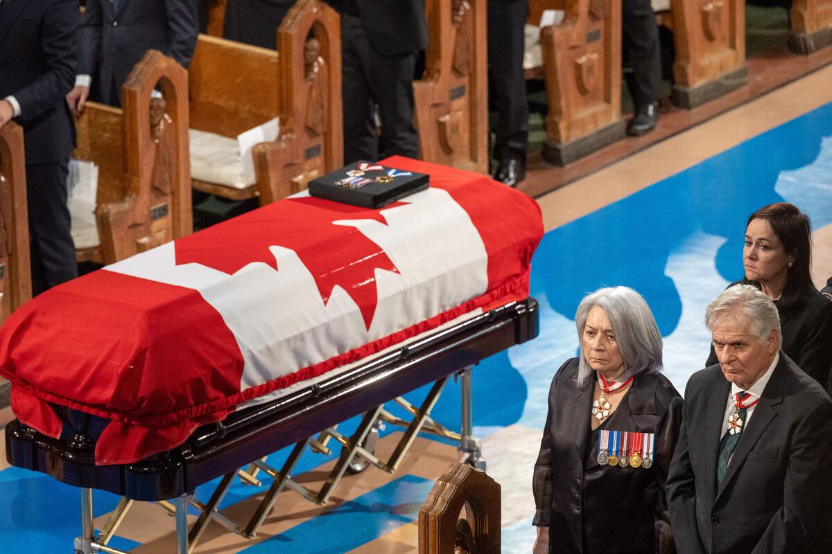 Governor General Mary Simon and Mr. Whit Fraser stand next to the casket
