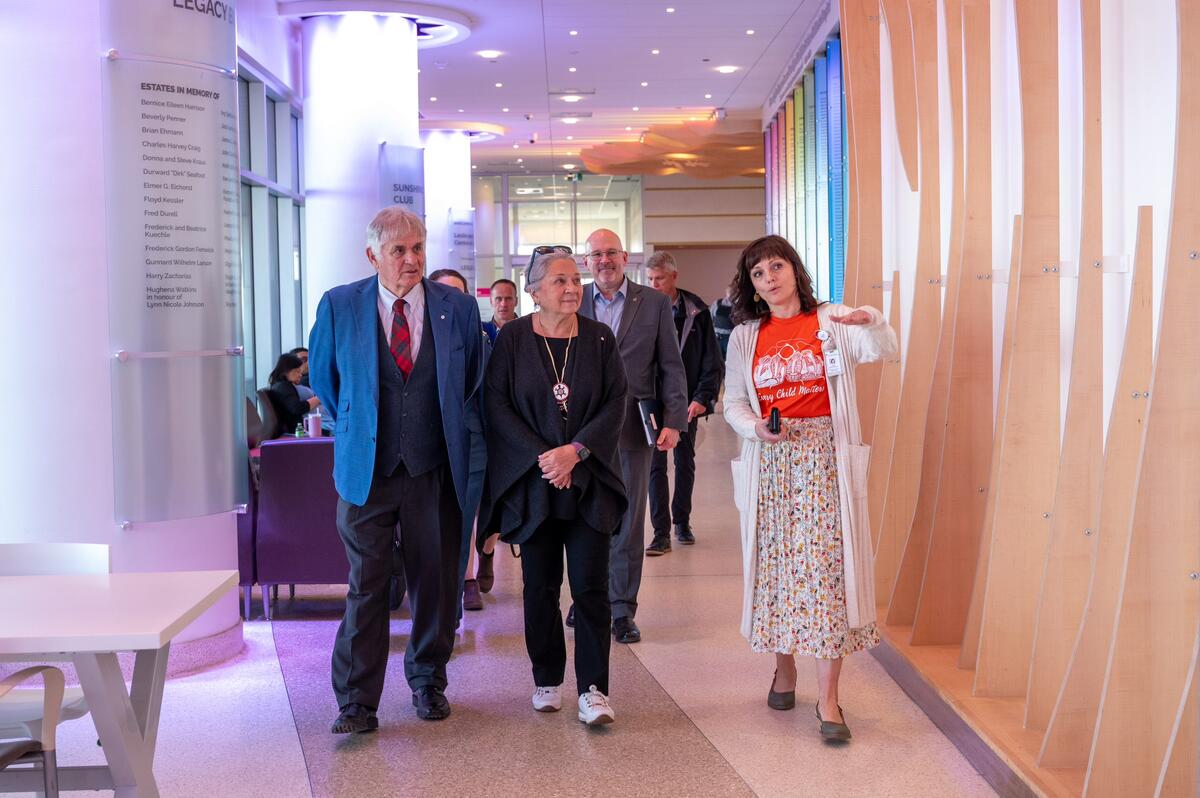 Governor General Simon and Mr. Whit  Fraser walking with a group of people in a hospital hallway.