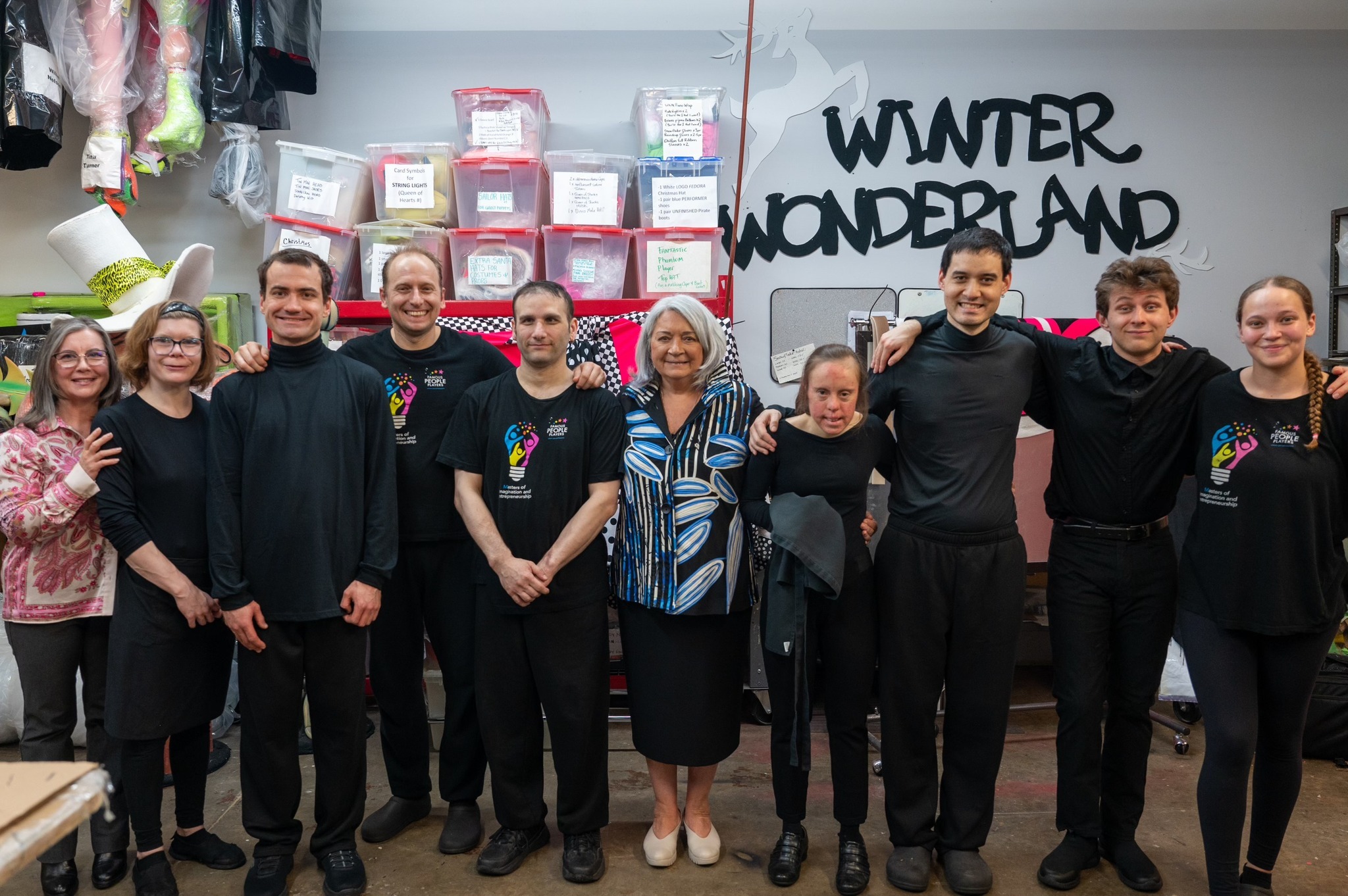 La gouverneure générale Mary Simon se tient au milieu d'une file de personnes, dont la plupart sont vêtues de noir. Derrière eux, plusieurs boîtes sont empilées. Sur le mur du fond, on peut lire « Winter Wonderland » (Royaume d’hiver).