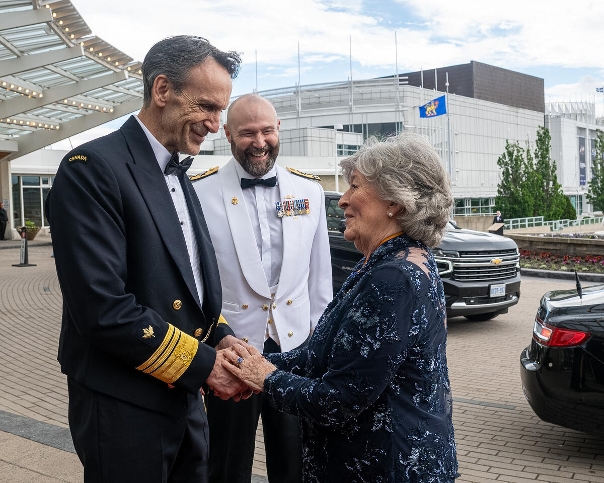 Governor General Arbour shaking hands with man in naval attire while another man in naval attire smiles nearby.