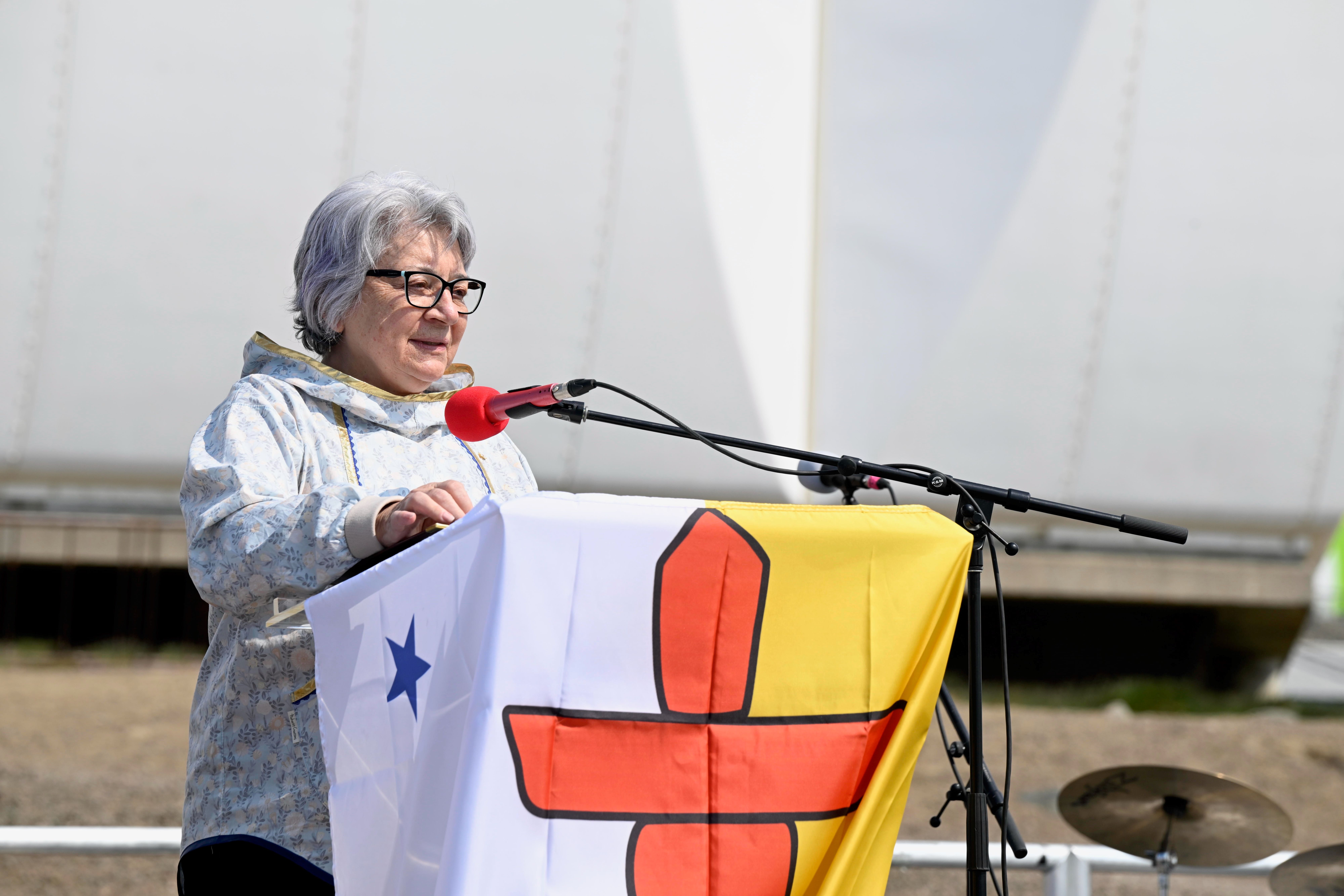 Governor General Mary Simon stands at a podium draped in the Nunavut flag.