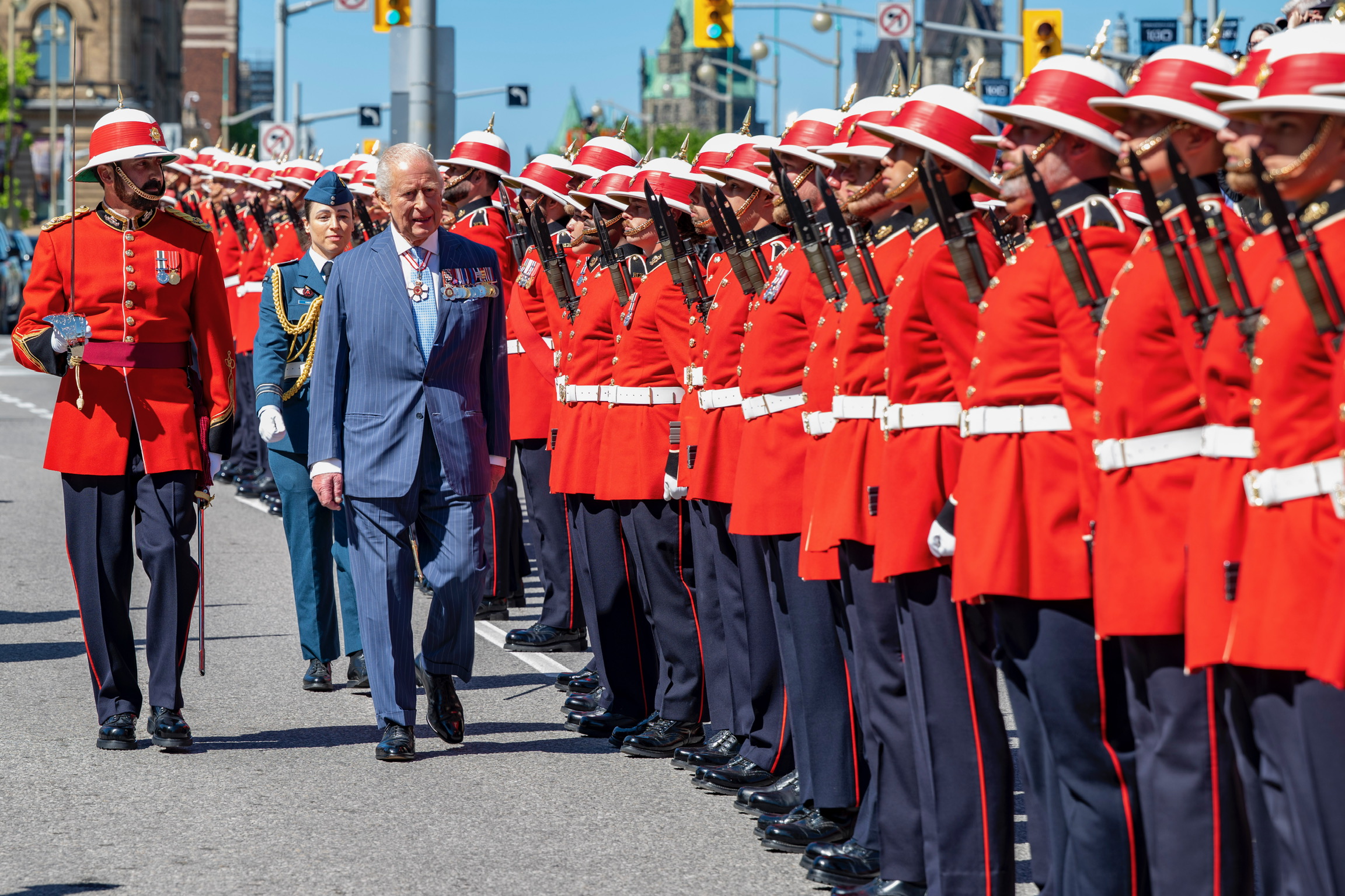 Sa Majesté inspecte une garde d'honneur dans la tradition militaire officielle.