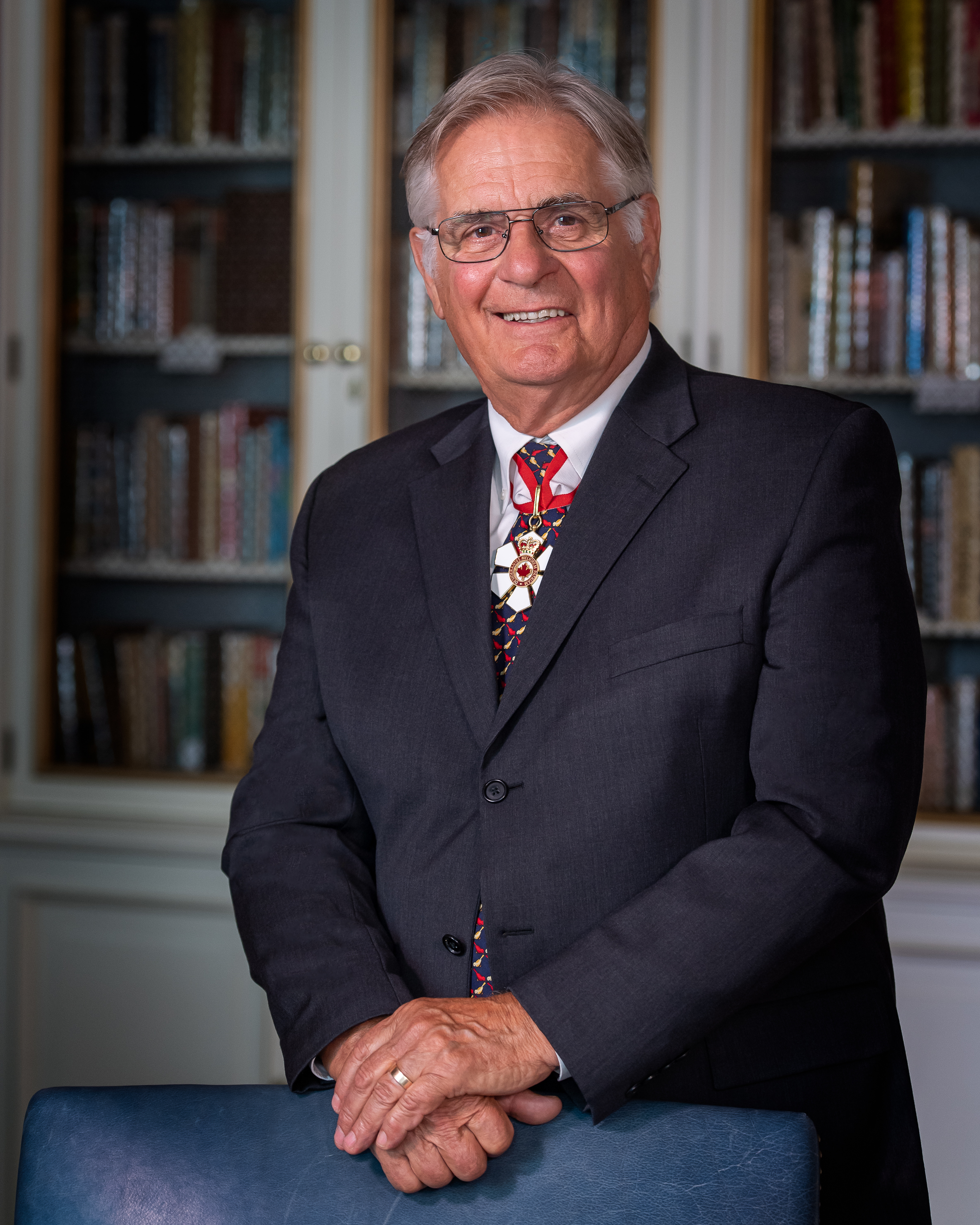 Photo officielle de Son Excellence Whit Grant Fraser. Des étagères de livres sont visibles à l'arrière-plan.