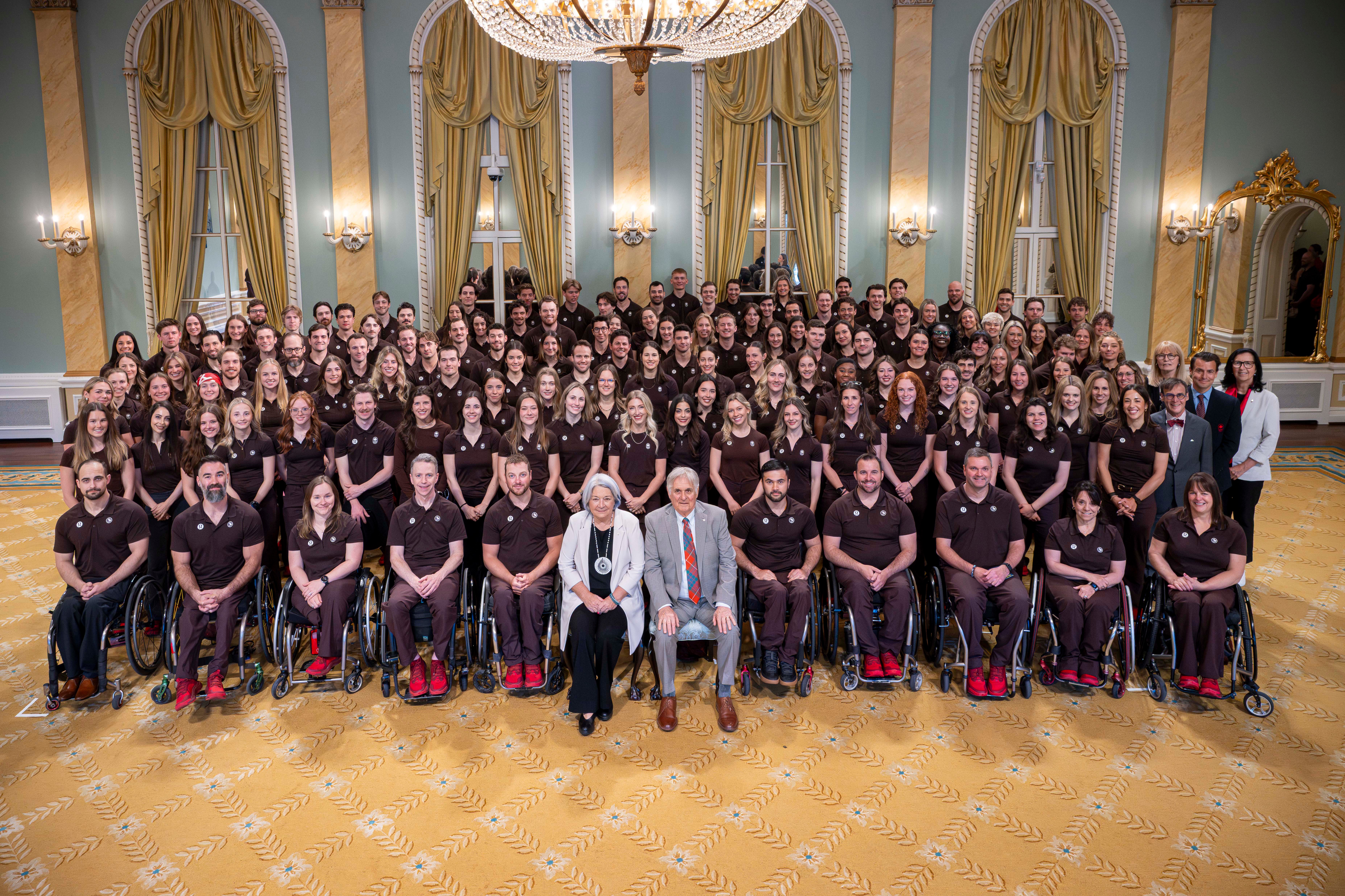 Governor General Mary Simon and Mr. Whit Fraser posing with Team Canada athletes.