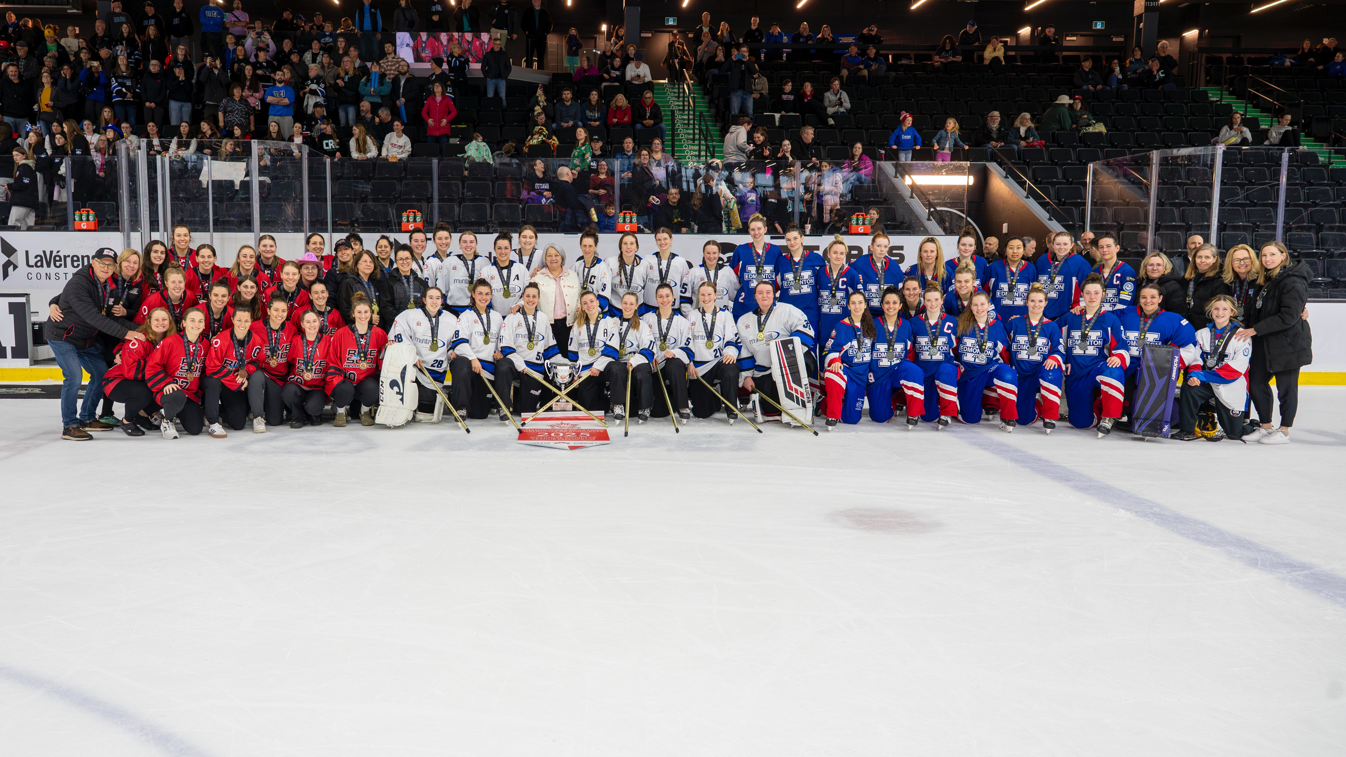 Photo de l'équipe de ringuette avec la gouverneure générale Mary Simon. Le trophée est devant tout le monde sur la glace.