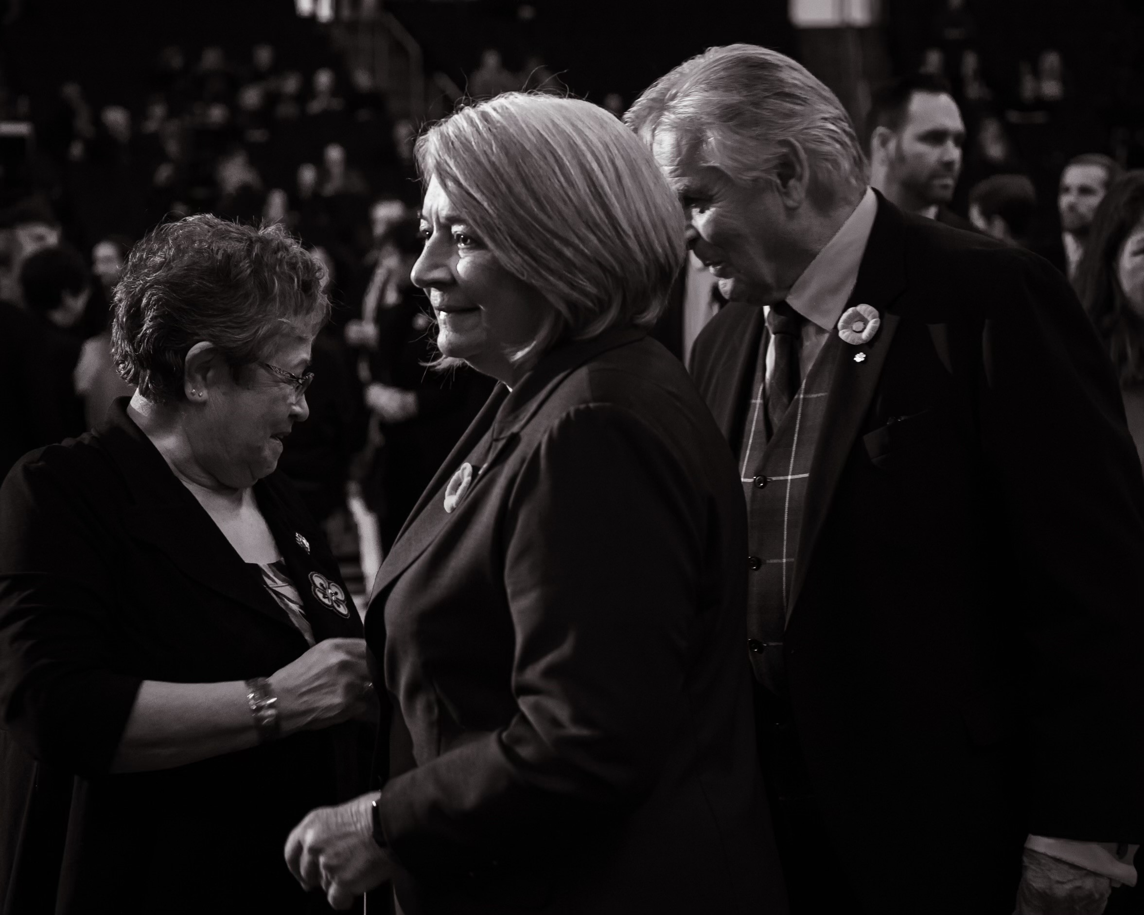 Black and white photo. Governor General Mary Simon is shaking a person's hand. Her husband, Mr. Whit Fraser, is behind her.