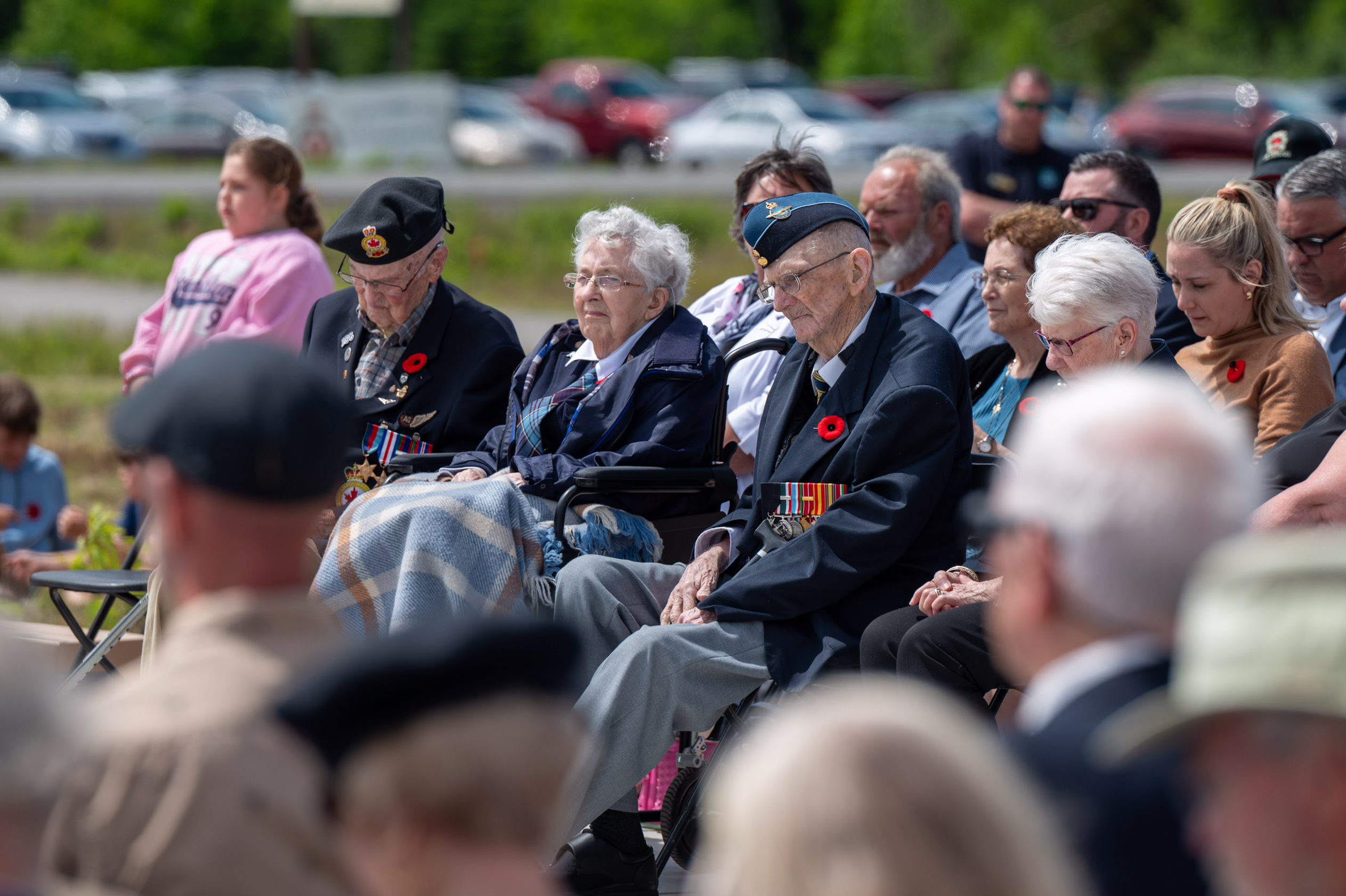 VLes anciens combattants participant à la cérémonie s'assoient et écoutent dans la foule rassemblée