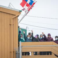 A crowd of people is waving outside the airport.
