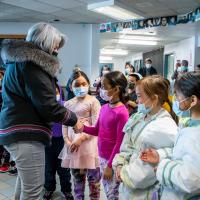 The Governor General is shaking hands with a young girl at school.