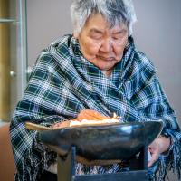 A woman has a bowl of fire in front of her.