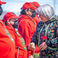Governor General Mary Simon shaking hands with a row of people dressed in red sweatshirts.