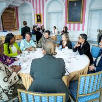 A group of women engage in conversation at a round table with Governor General Simon, in the Tent Room at Rideau Hall.