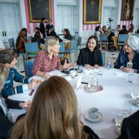A group of women engage in conversation at a round table with Governor General Simon, in the Tent Room at Rideau Hall.