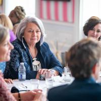 A group of women engage in conversation at a round table with Governor General Simon, in the Tent Room at Rideau Hall.