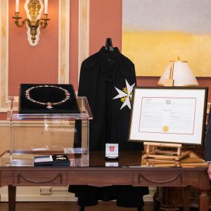 The Governor General and a man stand on either side of a table that features medals, decorations and a certificate.