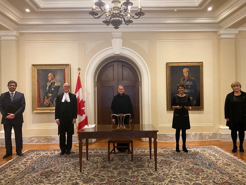 The Governor General is standing behind a table. Four people are standing on either side of her, all while maintaining social distancing norms. 