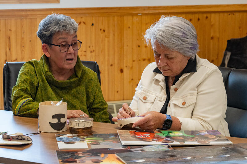 La gouverneure générale Mary Simon en train de coudre quelque chose. Elle est assise à une table avec une autre personne.
