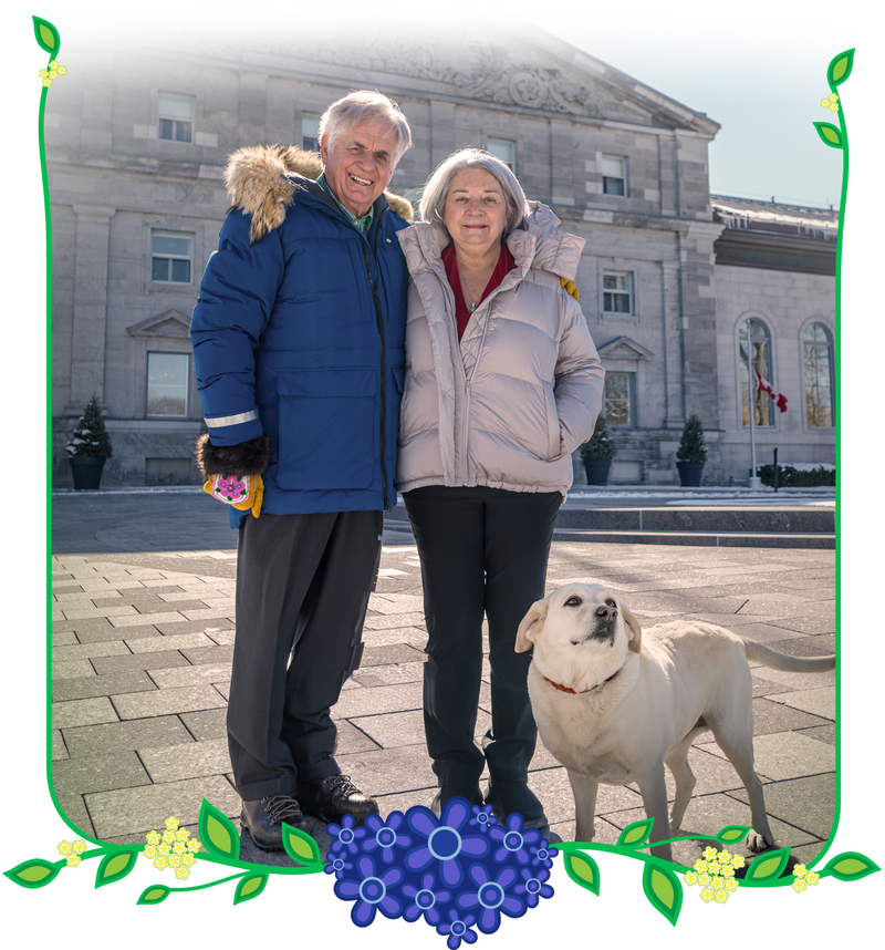 Governor General Mary Simon and Mr. Whit Fraser posing for a holiday photo with their dog.