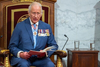 His Majesty King Charles III sitting on a throne.