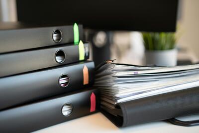 Stack of black binders on a desk.