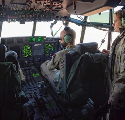 La gouverneure générale Julie Payette regarde un pilote et son co-pilote à l'oeuvre dans un cockpit d'avion.