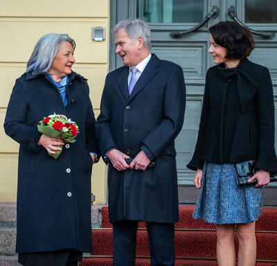 Holding a bouquet of flowers, Governor General Simon stands next to President Sauli Niinistö and his spouse, Dr. Jenni Haukio.