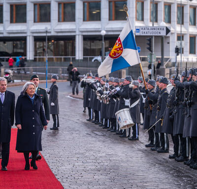 Governor General Simon and President Sauli Niinistö walking down a red carpet. They are inspecting a guard of honour.