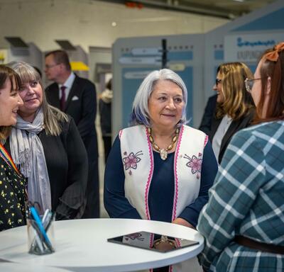 Governor General Simon standing with several women. The woman on her left is speaking to her.
