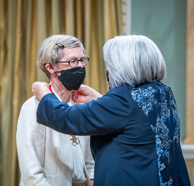 The Governor General is placing a medal around Robin McLeod’s neck.