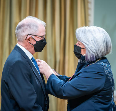 The Governor General is placing a pin on Thomas J. Foran’s suit jacket.