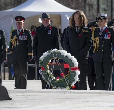  The Governor General salutes as she stand in front of a wreath.  Her son stands to her left.  Behind them is a row of people that includes the Chief of the Defence Staff, General Jonathan Vance.  