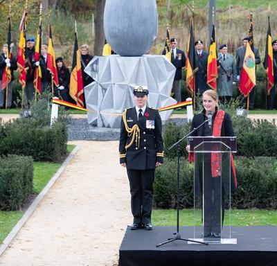 The Governor General of Canada is speaking at a podium, with her female Aide-de-camp on her right side. A giant concret sculpture in the shape of a teardrop is behind her.