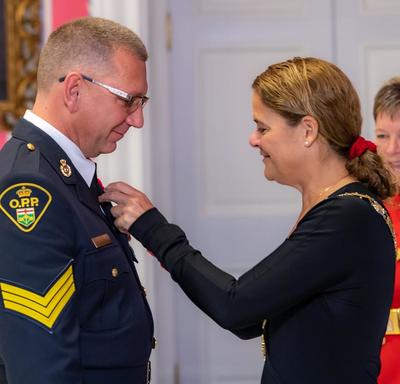 The Governor General pins a medal on the chest of a recipient of the Order of Merit of the Police Forces.
