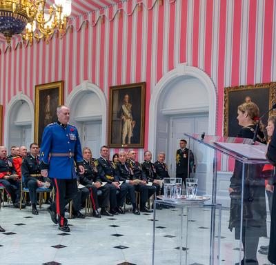 A recipient of the Order of Merit of the Police Forces walks to the front of the tent room to accept his medal.