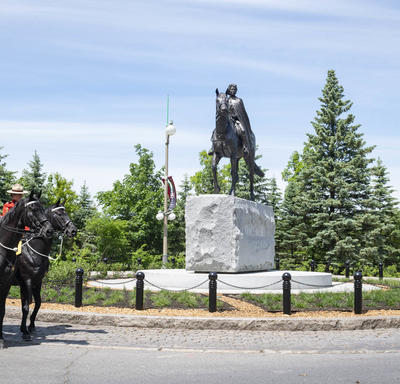 The horses from the RCMP Musical Ride are standing beside the Queen Elizabeth II Equestrian Monument.