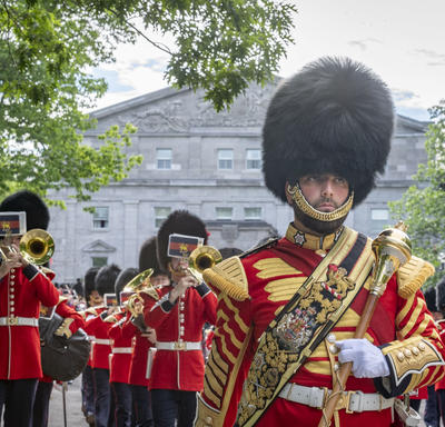 The Band of the Ceremonial Guard marches away from the Rideau Hall entrance while providing musical support.