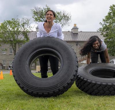 Two women are flipping tires as part of an obstacle course. 
