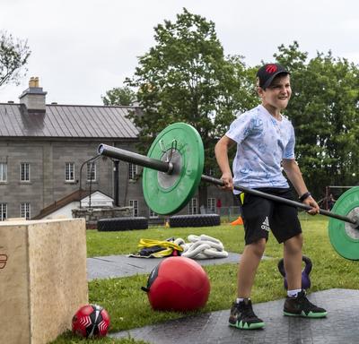 A child is lifting weights as part of an obstacle course. 