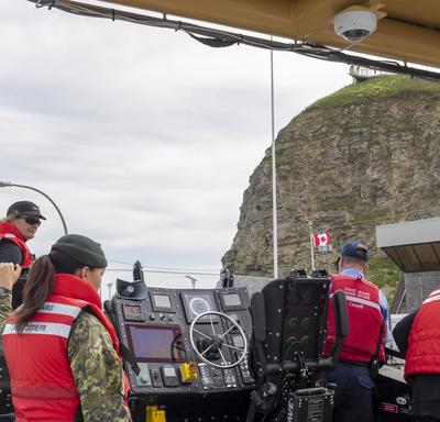 A photo of the CCGS Baie de Plaisance and crew at sea performing a search and rescue demonstration.
