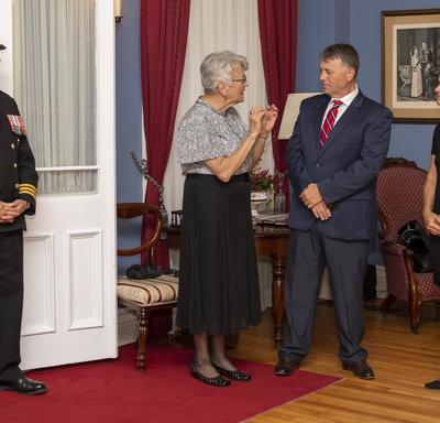 (Left to Right) a photo of an officer, Her Honour the Honourable Antoinette Perry, the Honourable Dennis King, and Her Excellency the Right Honourable Julie Payette, inside Government House.