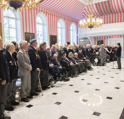 A large group of veterans stand in solidarity during the singing of the National Anthem at the launch of the 2019 National Poppy Campaign.