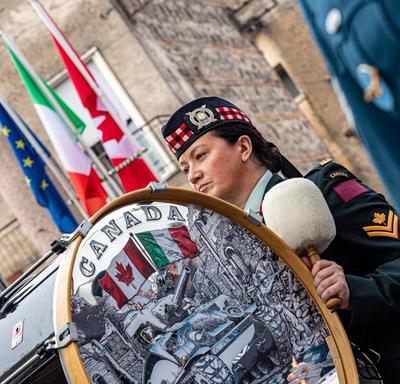 Un membre de l'orchestre de cornemuses et tambours des Forces armées canadiennes tient un tambour de cuivre.