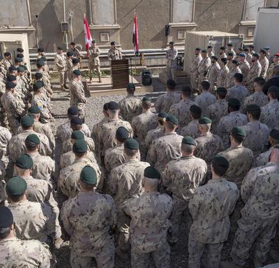 Des dizaines de membres des Forces armées canadiennes écoutent la Gouverneure générale Julie Payette prendre la parole à une tribune. 