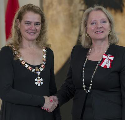 Agnes Di Leonardi stands next to the Governor General.  Both smile at the camera.  They are wearing their Order of Canada insignia.