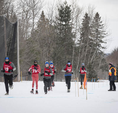 Athletes compete outdoors in a tight snowshoeing race.