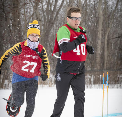 Athletes compete outdoors in a tight snowshoeing race.