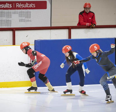 Des athlètes s'affrontent dans une course serrée de patinage de vitesse.