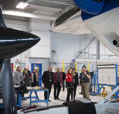 La gouverneure générale dans le hangar du Centre d'excellence en aviation avec des élèves, des enseignants et des avions.