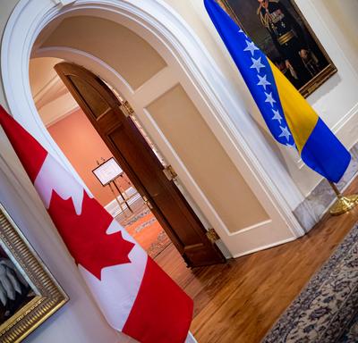 The Canadian and Bosnia and Herzegovina flags are on either side of a door. 