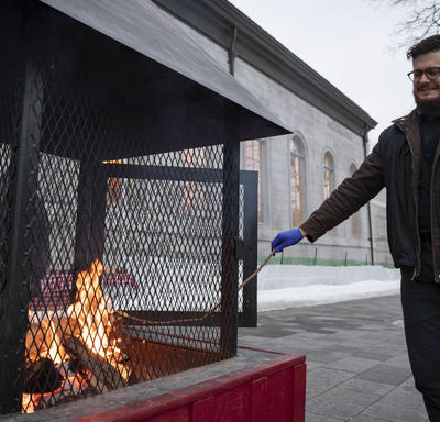 A photo of a man roasting a marshmallow on a fire at Rideau Hall. 